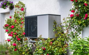 outdoor unit of a heat pump heating system surrounded by flowers