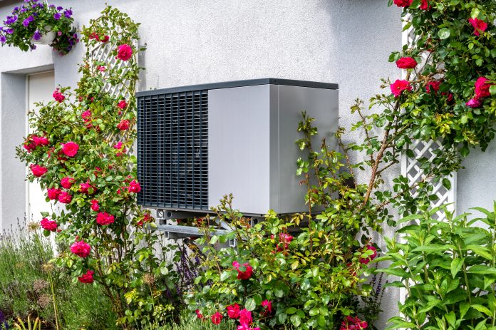 outdoor unit of a heat pump heating system surrounded by flowers