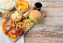 fast food, junk-food and unhealthy eating concept - close up of fast food snacks and coca cola drink on wooden table