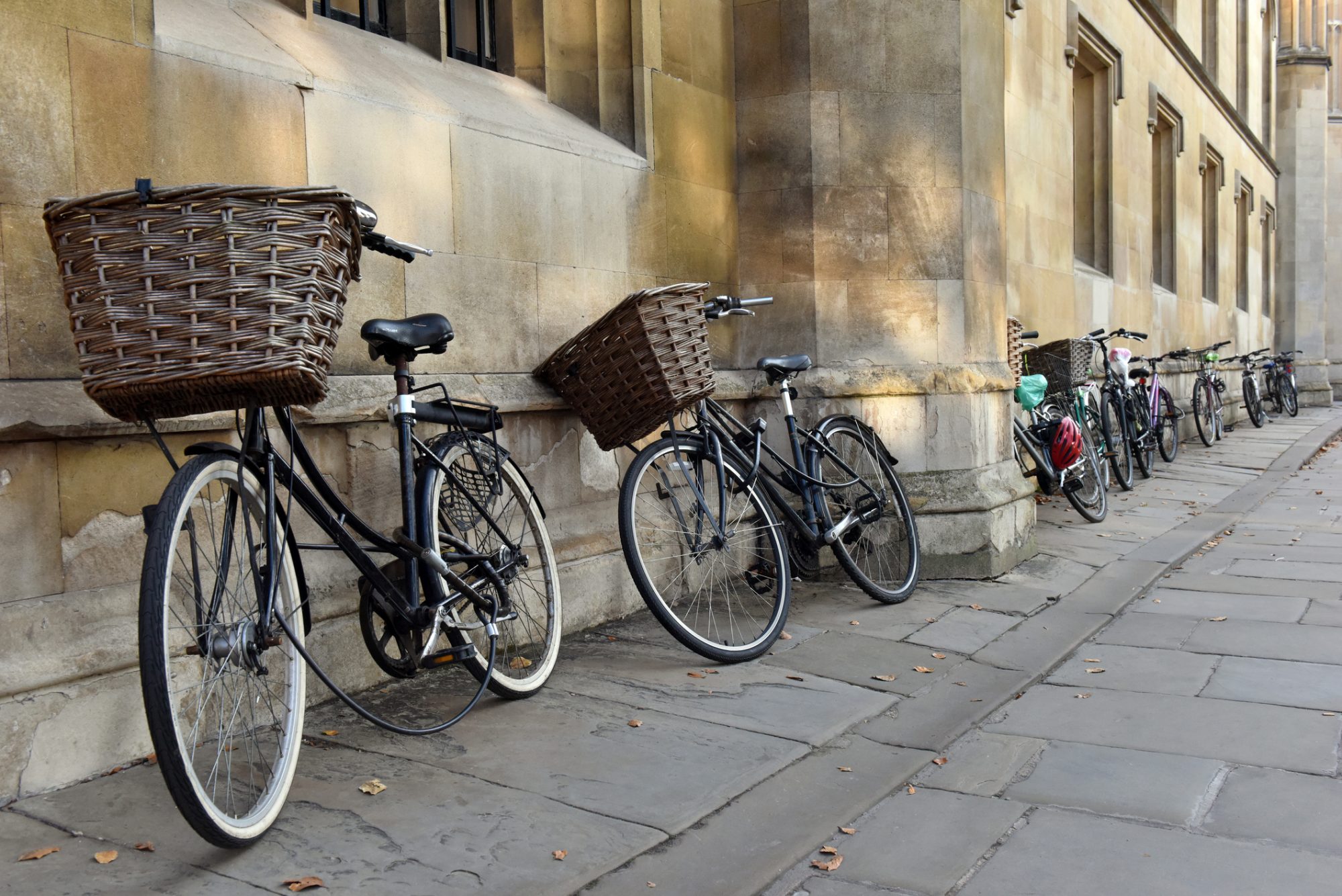 Traditional bicycles with baskets parked by students in a Cambridge street near a college