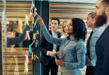 Creative group of business people brainstorming putting sticky notes on glass wall in office