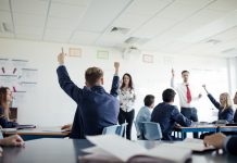 Teenage female student raising her hand to answer a question.