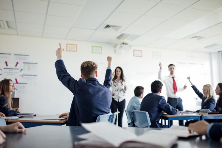 Teenage female student raising her hand to answer a question.