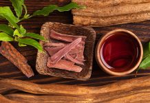 Ayahuasca brew with baniseriopsis caapi mimosa hostilis rootbark and chackruna leaves on wooden table from above.