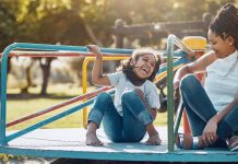 Shot of a mother and her daughter playing together on a merry-go-round at the park