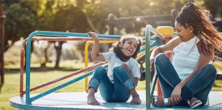 Shot of a mother and her daughter playing together on a merry-go-round at the park