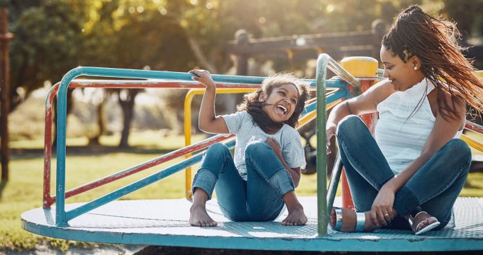 Shot of a mother and her daughter playing together on a merry-go-round at the park