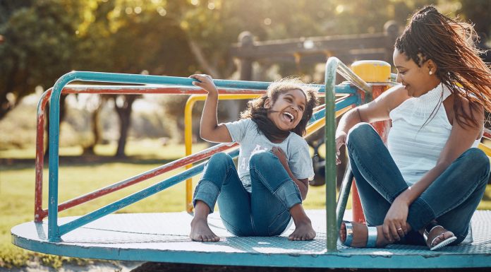 Shot of a mother and her daughter playing together on a merry-go-round at the park