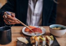 One man, gentleman sitting in restaurant alone, he is eating sushi.