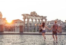 Young couple tourist walking pointing towards Roman Forum at sunrise. Historical imperial Foro Romano in Rome, Italy from panoramic point of view.