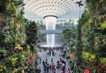 Jewel Changi Airport, Singapore - 5th August, 2019: Visitors tour around the Rain Vortex inside the Jewel area at Changi Airport. It's the world's tallest waterfall at 130 ft in height and surrounded by a four-storey terraced forest. The Jewel complex and waterfall was designed by Moshe Safdie.