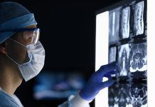 Male doctor in surgical clothes looking at vertebral mri scan headshot