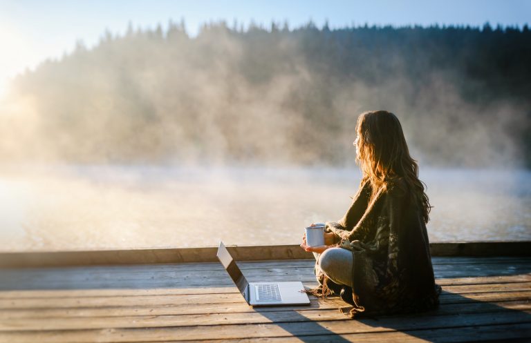 Young woman working on laptop in the nature . Leisure activities / Remote working concept.