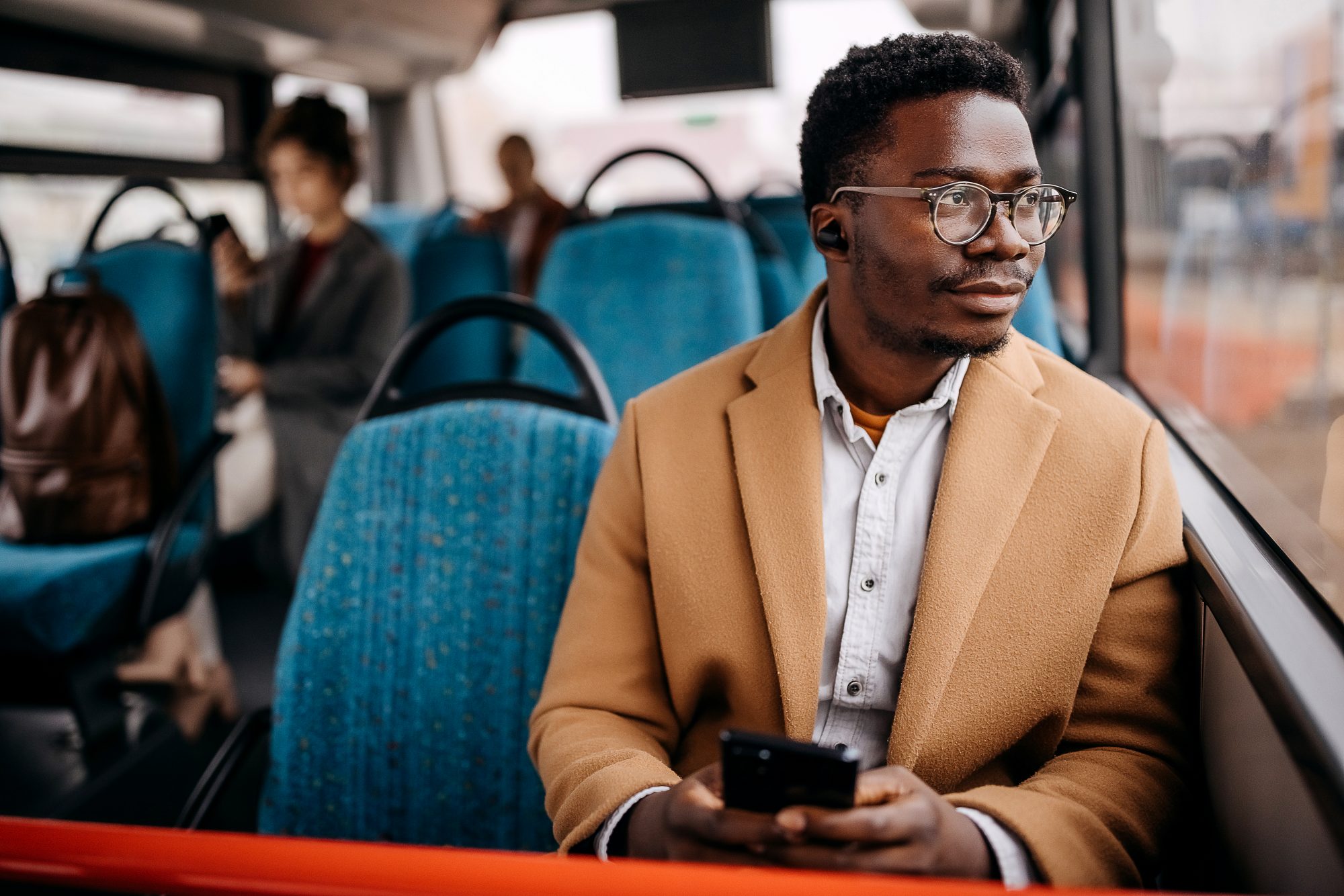 Young handsome man on public bus using mobile phone