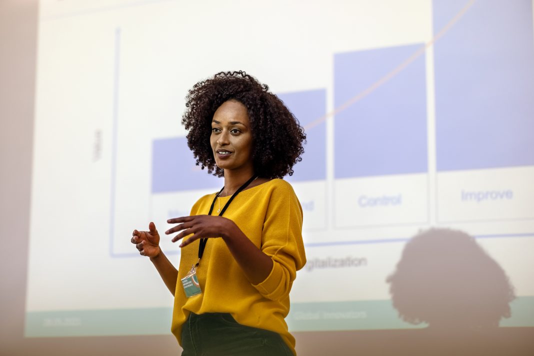 Woman entrepreneur speaking in the auditorium at the corporate training event. Woman at seminar giving a presentation.