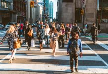 Crowd of unrecognisable people crossing street on traffic light zebra in the city of Toronto at rush hour - Lifestyle in a big city in North America