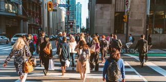 Crowd of unrecognisable people crossing street on traffic light zebra in the city of Toronto at rush hour - Lifestyle in a big city in North America