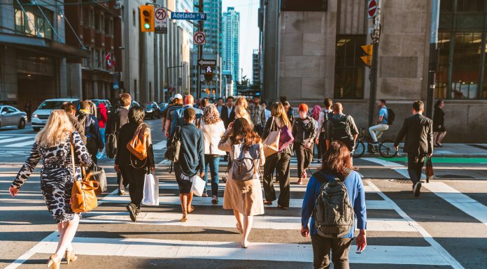 Crowd of unrecognisable people crossing street on traffic light zebra in the city of Toronto at rush hour - Lifestyle in a big city in North America