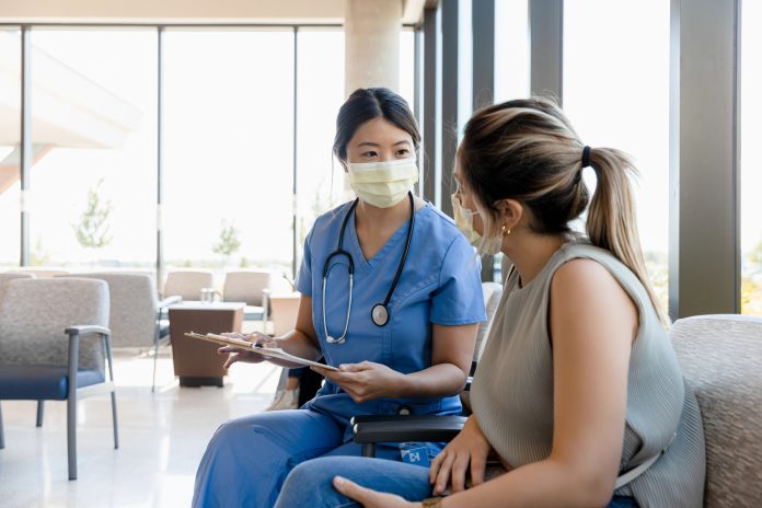 The mid adult female surgeon goes out to the waiting room to ask the young adult woman for information about the patient.