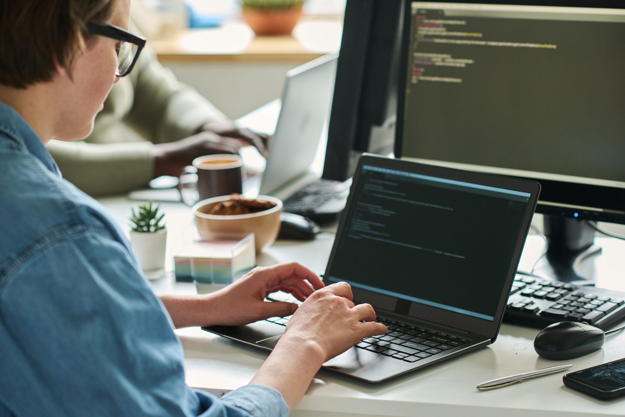 Female programmer writing codes on laptop at table to get access to website