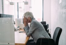 Stressed woman working in modern office. Frustrated businesswoman with head in hands sitting on desk in the office.