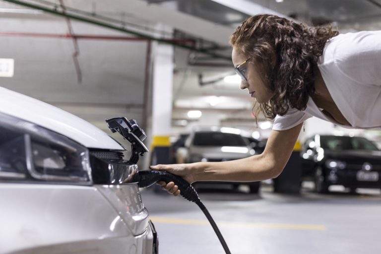 Woman refueling and charging an electric vehicle in a garage