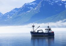 "Large fishing boat anchored in Valdez, Alaska bay. Chugach Mountains in background."