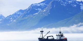 "Large fishing boat anchored in Valdez, Alaska bay. Chugach Mountains in background."