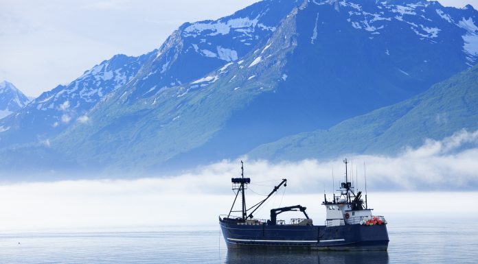 "Large fishing boat anchored in Valdez, Alaska bay. Chugach Mountains in background."