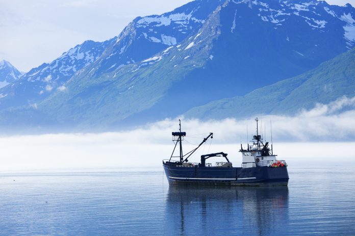 "Large fishing boat anchored in Valdez, Alaska bay. Chugach Mountains in background."