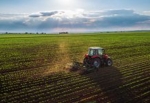 Tractor cultivating field at spring,aerial view - EU green deal environmental commitments farmers