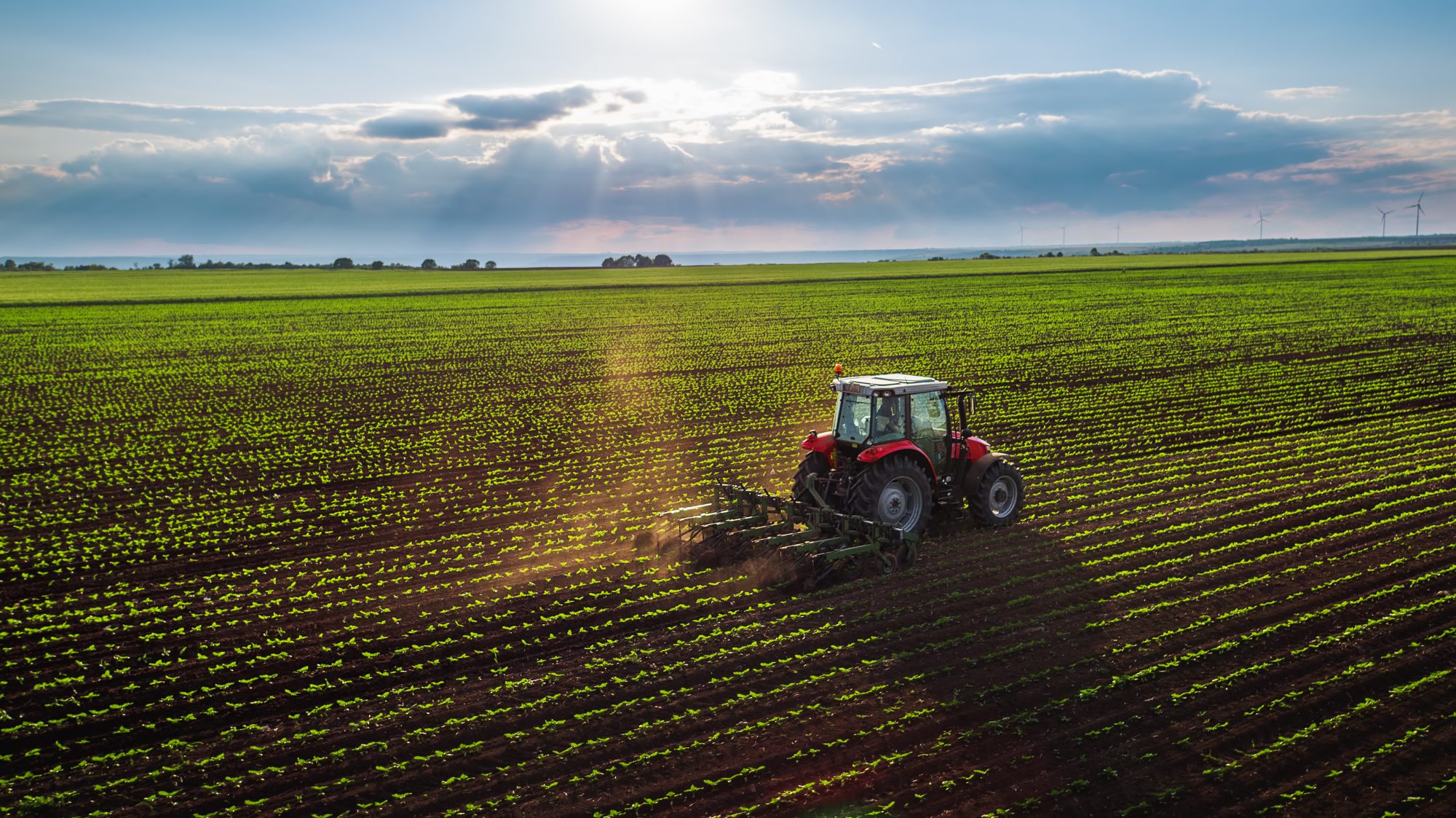 Tractor cultivating field at spring,aerial view - EU green deal environmental commitments farmers