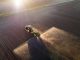 Aerial image of tractor spraying soil and young crop in springtime in field