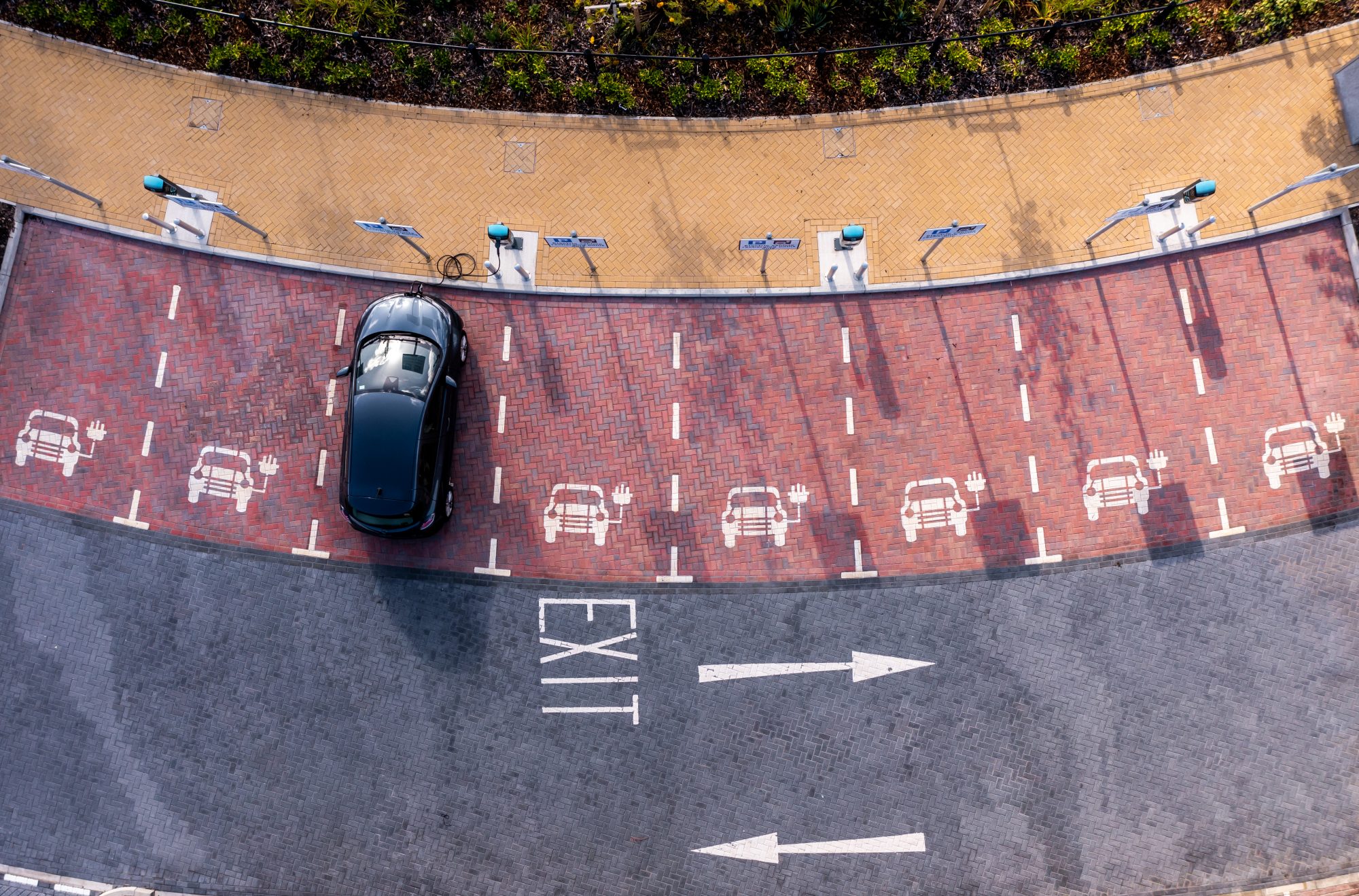 An aerial view directly above an electric vehicle charging station with electric car charging in a parking space