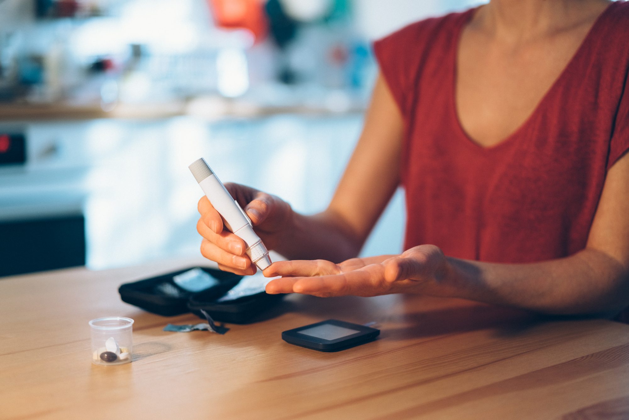 Woman at home checking blood sugar levels with glaucometer