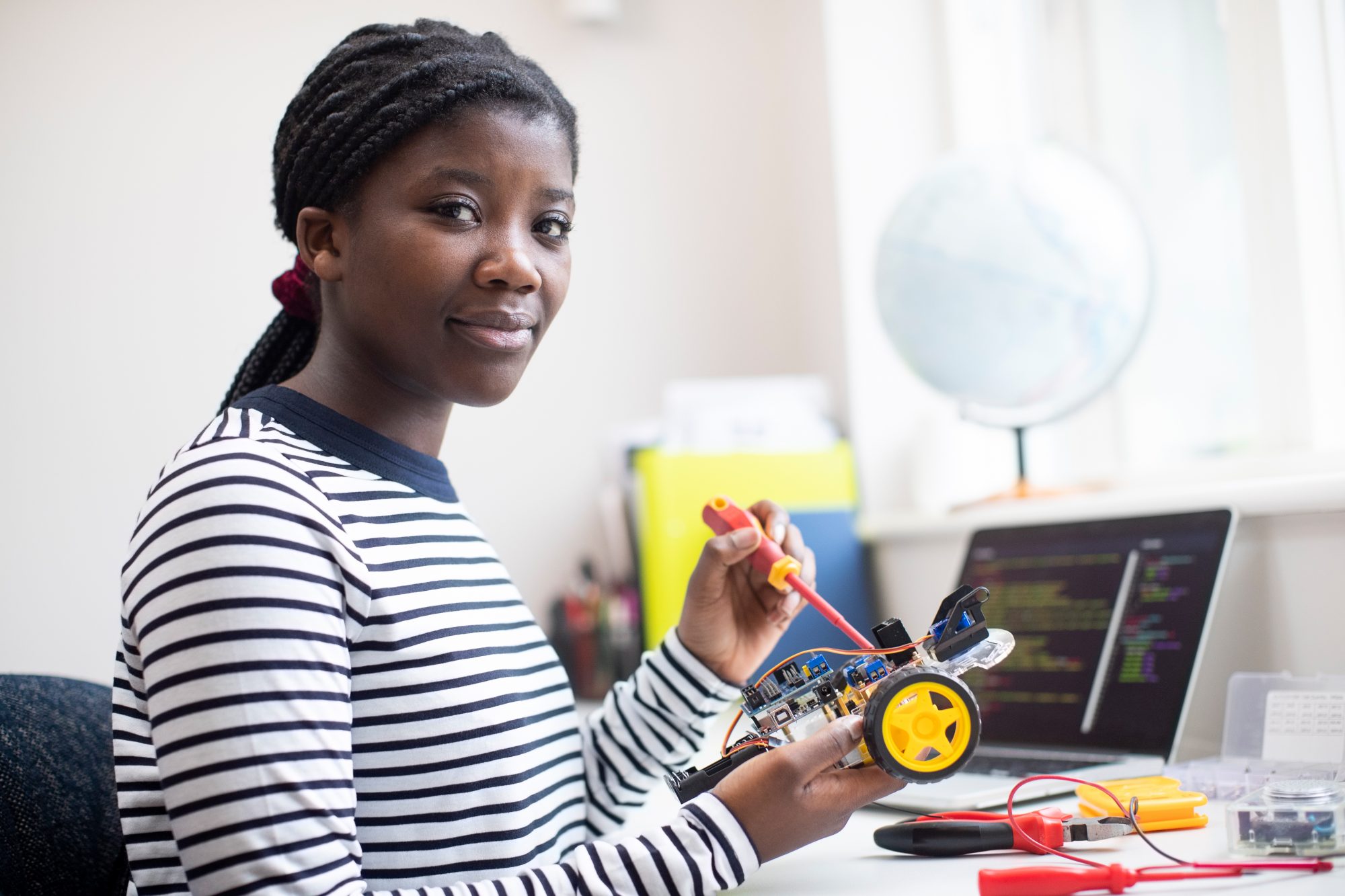 Portrait Of Female Teenage Pupil Building Robot Car In Science Lesson