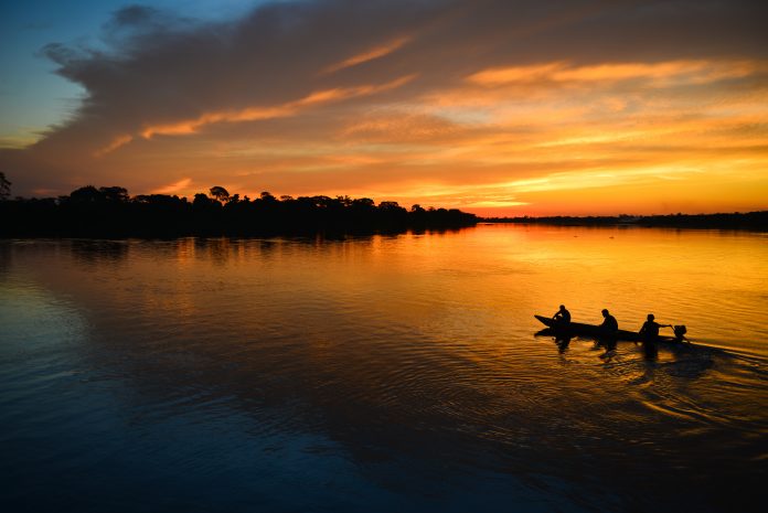 A small motorized canoe on the Guaporé - Itenez river during sunset, Ricardo Franco village, Vale do Guaporé Indigenous Land, Rondonia, Brazil, on the border with Bolivia