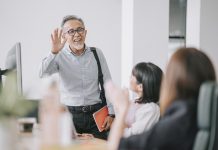 working asian chinese senior colleague back to work with face mask greeting on each other in office morning