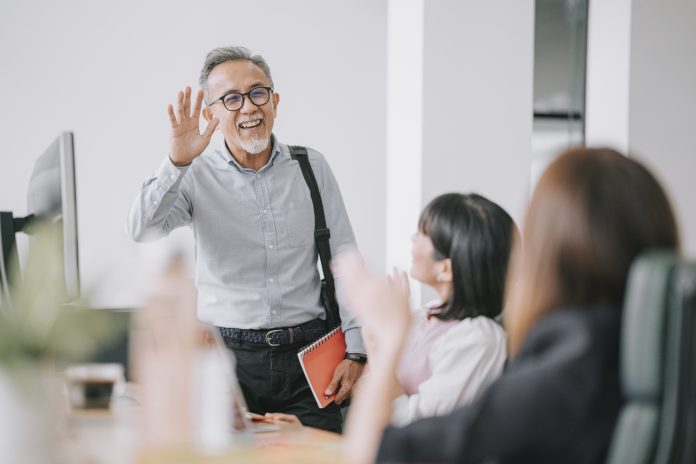 working asian chinese senior colleague back to work with face mask greeting on each other in office morning