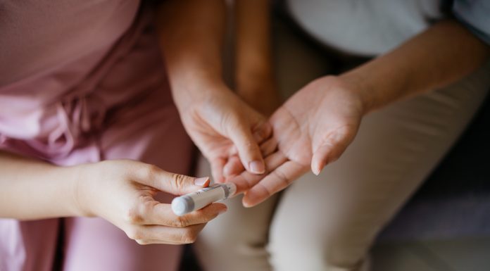 Close-up woman helping her mother check blood sugar level at home