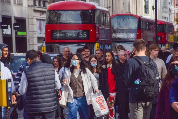 London, UK - October 26 2021: People wearing protective face masks on a busy Oxford Street during the coronavirus pandemic.