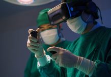 Professional surgeons in uniform and VR headset performing operation on patient in modern clinic