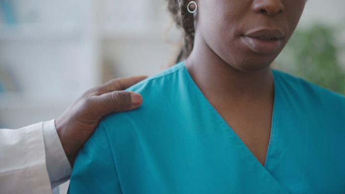 Male physician touching female colleague's shoulder, sexual harassment at work place