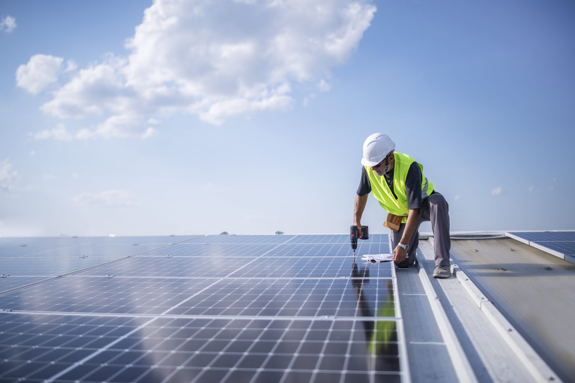 Man on roof installing solar panel system.