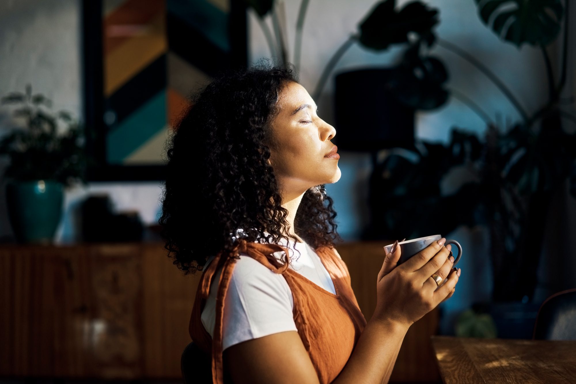 Relax, peace and coffee with a woman drinking a drink of caffeine and meditating in her home with her eyes closed. Mental health, wellness and zen with a young female enjoying calm, quiet tranquility