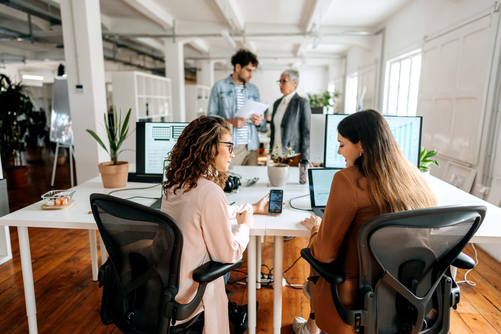 Two female colleagues analyze the crypto mobile app in the office