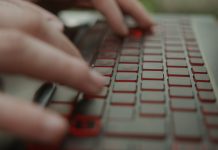 Close-Up of Laptop Keyboard and Hands Typing by Young Man