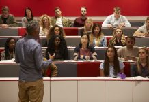 Back view of man presenting to students at a lecture theatre