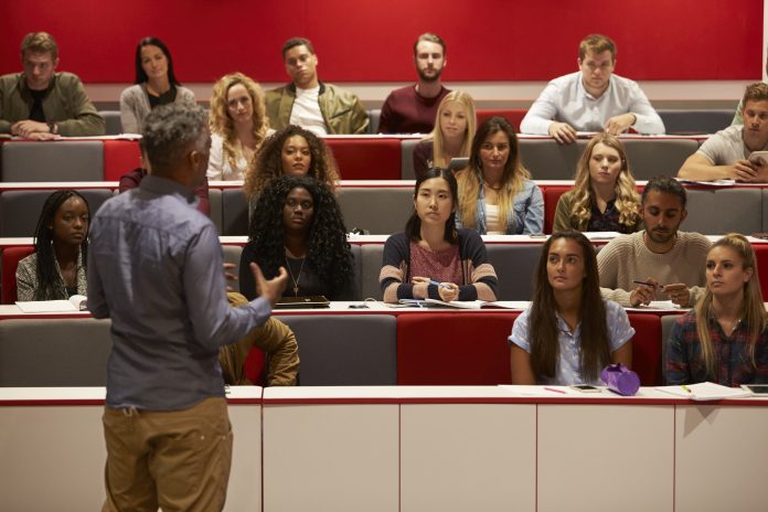 Back view of man presenting to students at a lecture theatre