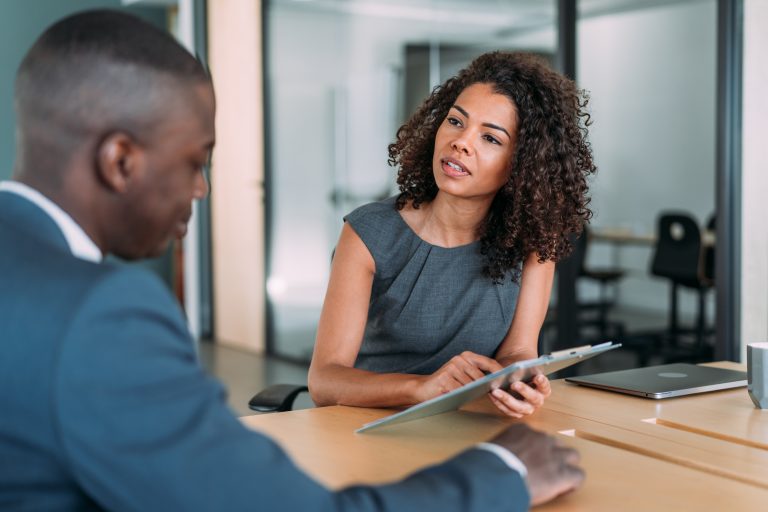 Shot of two colleagues having a discussion in the board room. Confident business people working together in the office. Corporate business persons discussing new project and sharing ideas in the workplace. Social dialogue taking place